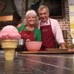 Paula Deen and Stratton Leopold locked in a side embrace, looking into the camera with ice cream in frame